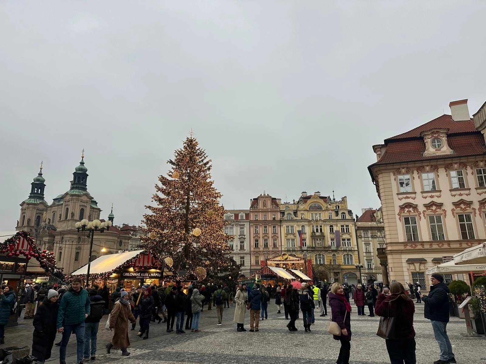 Mercado navideño en la Plaza de la Ciudad Vieja de Praga, República Checa, con un gran árbol de Navidad iluminado, puestos festivos y visitantes entre edificios históricos del centro de la ciudad.