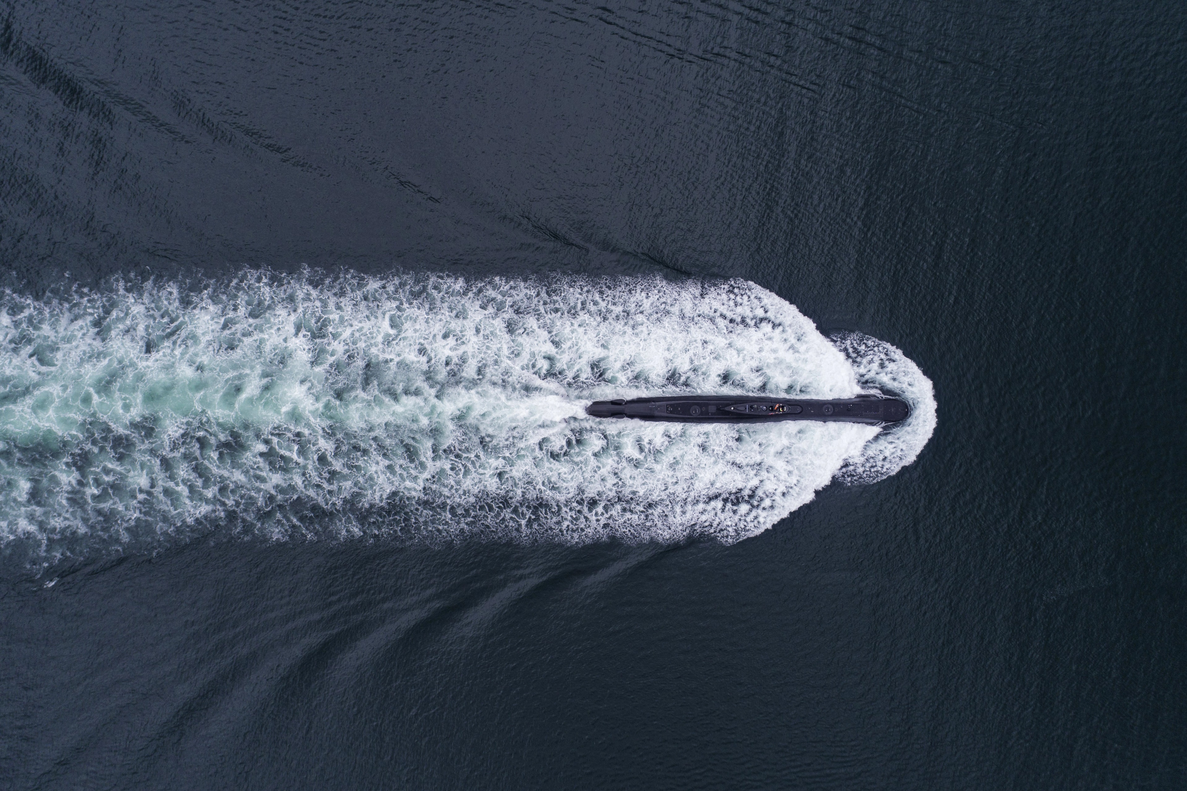 Vista aérea de una embarcación de alta velocidad navegando a toda marcha sobre aguas oscuras, dejando una estela de espuma blanca. Imagen ilustrativa tomada del sitio web de Palantir Technologies.