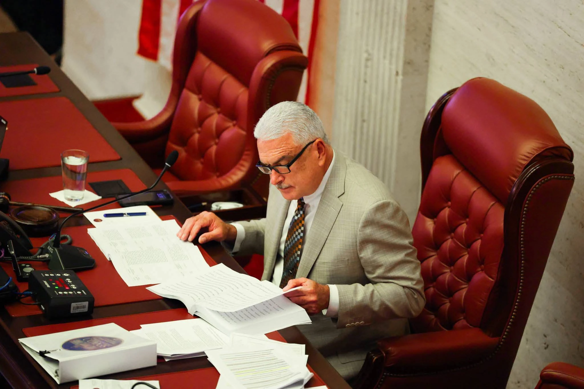 Thomas Rivera Schatz, presidente del Senado de Puerto Rico, sentado en su escaño y leyendo documentos oficiales durante una sesión en el Capitolio.
