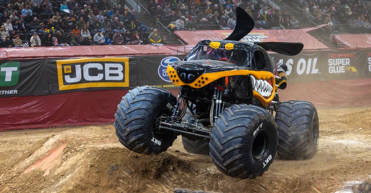 El camión Monster Mutt Rottweiler realiza una maniobra sobre una rampa de tierra durante el espectáculo de Monster Jam, frente a una multitud en una arena deportiva; evento confirmado para el Coliseo de Puerto Rico del 31 de octubre al 2 de noviembre de 2025.